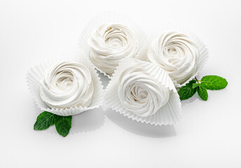 Small white meringues on a white background.
