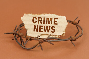 On a brown surface, barbed wire and a cardboard sign with the inscription - crime news