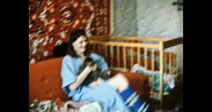 Young mother with pet, small child play in home room. Happy, smiling woman holding cat in arms. Shows an animal to baby girl. Family life indoors. Vintage color film. Family archive. Retro 1980s. 4k
