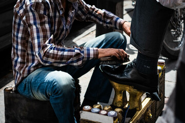 cleaning and polishing leather shoe on street