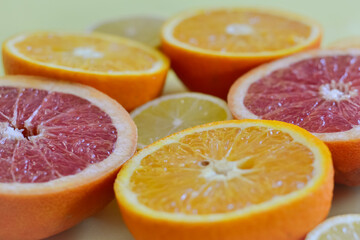Photo of oranges and citruses cut in half on a yellow background