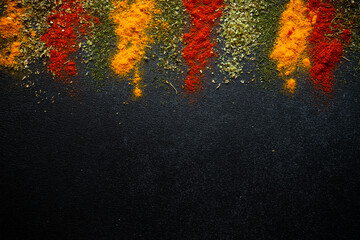 Spices powder on black slate background top view.