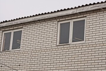 white brick attic of a private house with windows against a gray sky