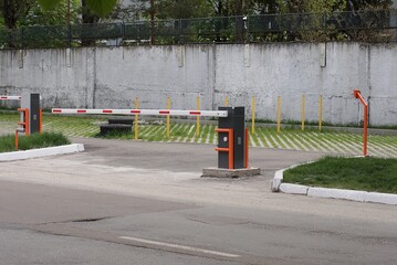  closed white red automatic barrier on the street on asphalt against a gray concrete wall