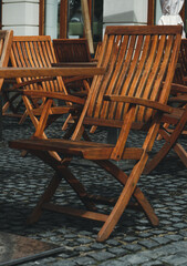 There are no people on the wooden terrace, on which there are wooden chairs, on the dark wooden floor. A deserted street cafe with wooden chairs. Street cafe, bistro, restaurant.