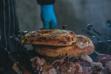 Cooking shish kebab on skewers. Meat, vegetables and bread rolls baked on coals.A male chef roasts juicy beef, chicken, pork.The concept of street food. Grilled meat on the grill.Meat on the barbecue.
