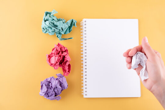 The Hand Crumpling The Page Of The Notebook On A Yellow Background. Space For Text. Turning Over A New Leaf