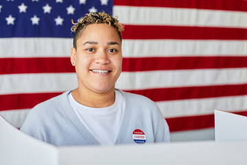 Portrait of smiling black woman voting against American flag background, copy space