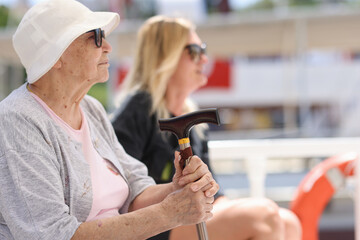 Elderly woman with cane sitting on bench