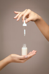 Female hands holding a dropper bottle filled with cosmetic fluid