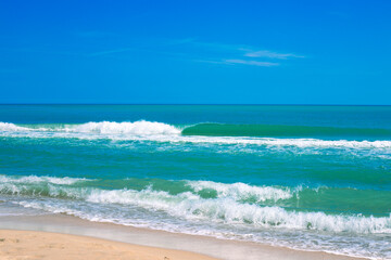 Fototapeta na wymiar Blue sea with a wave and a sandy shore, on the horizon with a blue sky. Seascape in summer