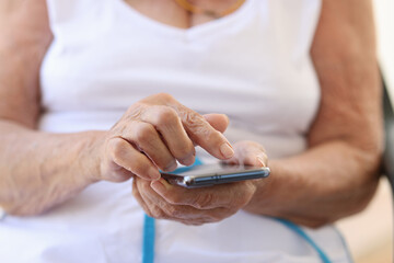 Old woman holding modern smartphone in hands