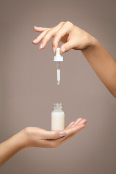 Female hands holding a dropper bottle filled with cosmetic fluid