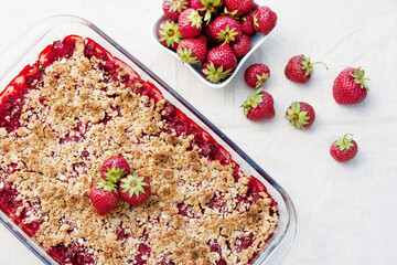 Homemade strawberry crumble is an English dessert. Baked berries covered with shortcrust pastry crumbs. Sweet and sour summer dessert. top view