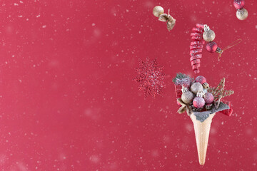 christmas decoration in ice cream cone on a red background behind the snow glass