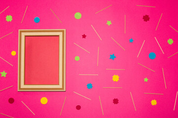 wooden retro frame with red copy space on the left side of the pink background, on the rest of the background wooden sticks and colorful geometric shape