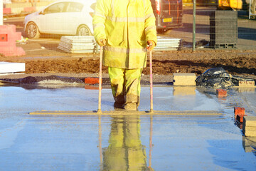 Builder pouring ground floor slab of a new house with wet ready-mix concrete, levelling it and...