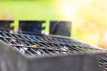 An empty grill with wood underneath burning and fire coming out of the top