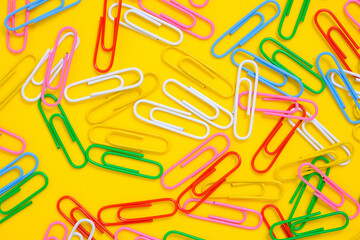 Colored paper clips on a yellow background.