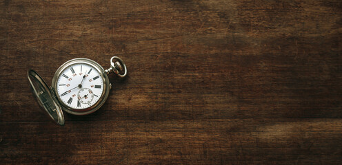 Vintage pocket watch on a rectangular wooden background.A clean place for the inscription. Mechanical watch with a double dial.