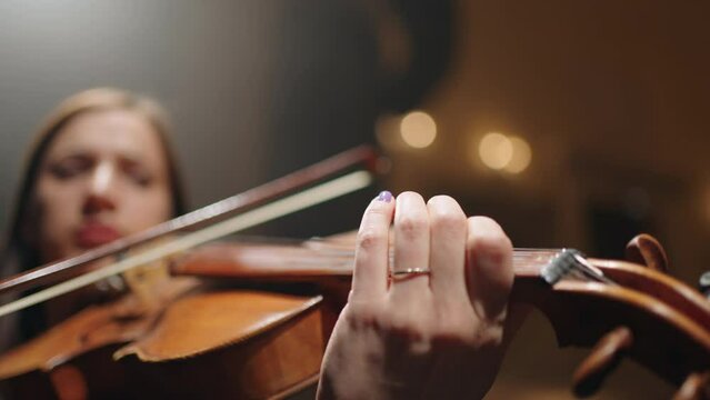 first violin in orchestra, closeup view of fiddle in hands of female musician, concert or rehearsal in opera house