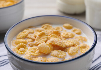 Tasty cornflakes with milk in bowl on table, closeup