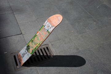 A skate board standing in a well or pockmark in the sidewalk or pavement