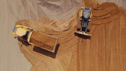 Drone photo of two machines - an excavator and a dump truck at work on a road construction project. High quality photo