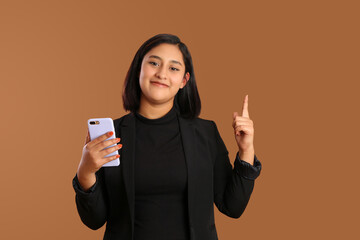 young mexican brunette business woman holding phone, smiling having an idea on plain brown...