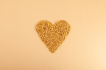 Fenugreek Seeds (Methi Dana) in heart shape on beige background. Shambhala or helba seeds is...