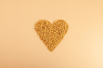 Fenugreek Seeds (Methi Dana) in heart shape on beige background. Shambhala or helba seeds is traditional Indian seasoning and ingredient Ayurvedic food. Used in culinary and medicine