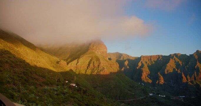Fog quickly descends into the gorge and the village of Maska. Beautiful mountain peak in clouds. Sunset on the gorge Mask or Masca village. Clouds descend on the gorge.