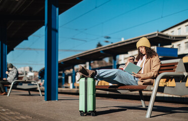 Young traveler woman sitting alone at train station platform with luggage.
