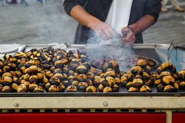 The cook roasts chestnuts in a kiosk on the street.