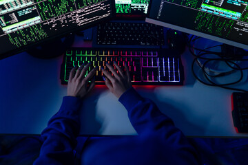 Close-up of woman hacker hands at keyboard computer in the dark room at night, cyberwar concept. Top view.