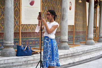 Person attaching a mobile to a tripod in the entrance of a buddhist temple