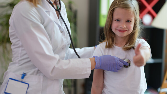 Happy Smiling Girl At Doctor Pediatrician Appointment Showing Thumb Up Sigh