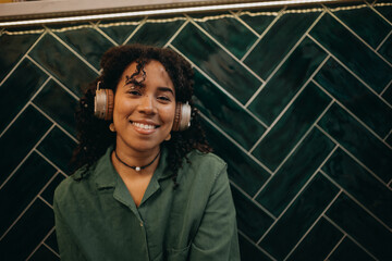 Young biracial woman wearing headphones and enjoying listening to music indoors.