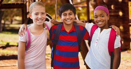 Portrait of smiling multiracial girls and boy with arm around standing at park
