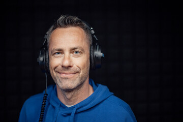 Portrait of male radio host with headphones in studio, looking at camera.