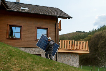 Man worker carrying solar panel for installing solar modul system on house.