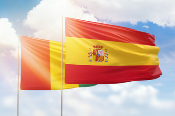 Sunny blue sky and flags of spain and guinea