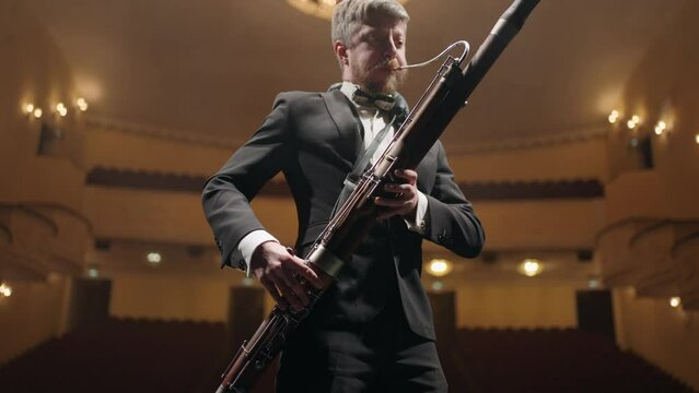 rehearsing in opera house or philharmonic hall, bassoonist is playing music on scene, portrait