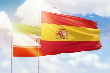 Sunny blue sky and flags of spain and iran