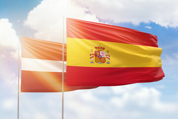 Sunny blue sky and flags of spain and latvia