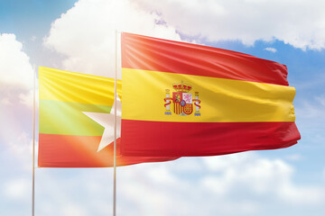 Sunny blue sky and flags of spain and myanmar