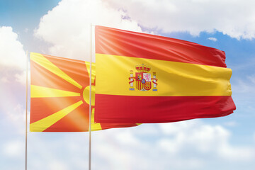 Sunny blue sky and flags of spain and north macedonia