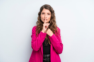 young adult pretty woman looking serious and cross with finger pressed to lips demanding silence or...