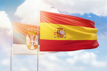Sunny blue sky and flags of spain and serbia