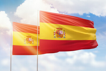 Sunny blue sky and flags of spain and spain